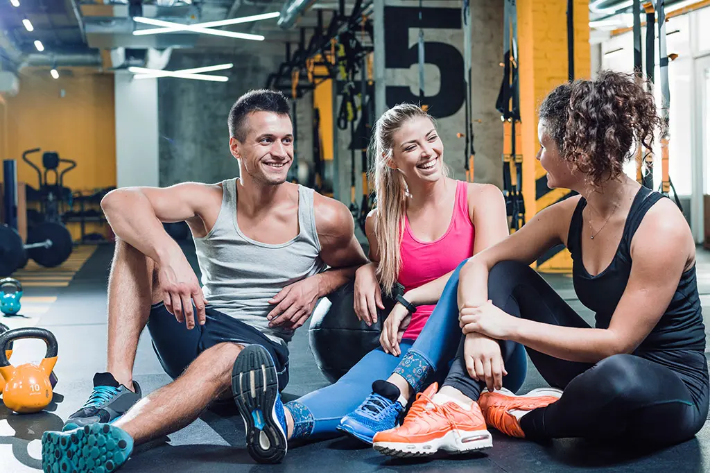 Muž a ženy se baví ve fitness centru při cvičení a sdílejí pozitivní sociální interakci a pohodu.