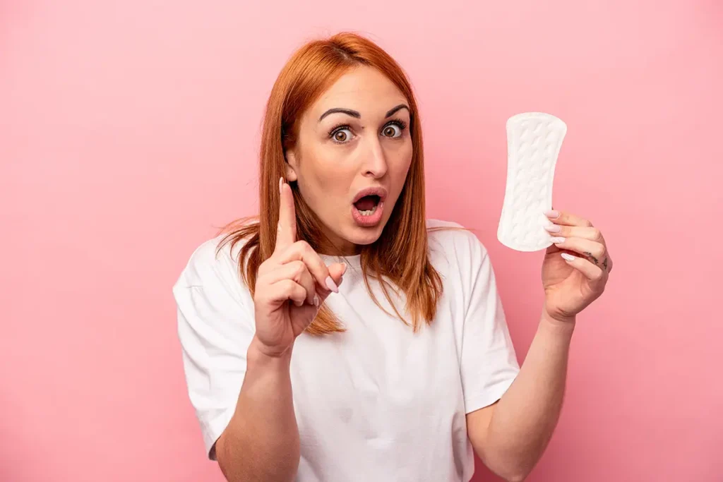 Žena držící dámskou vložku jako menstruační hygienickou pomůcku